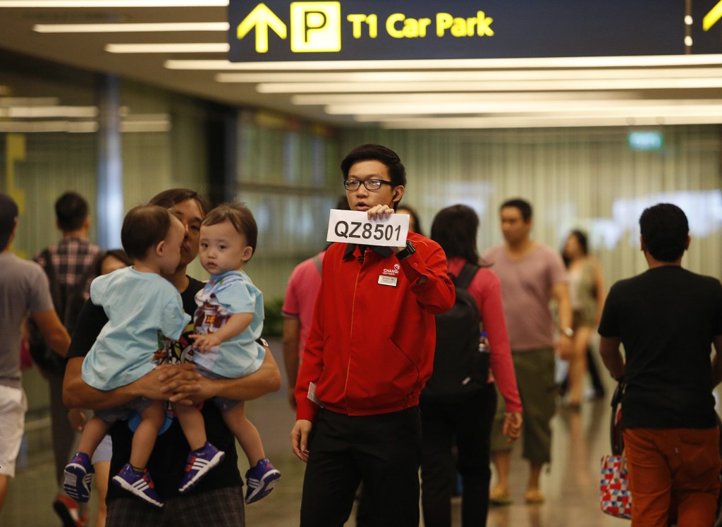 A Changi Airport staff holds up a sign to direct possible next-of-kins of passengers of AirAsia flight QZ 8501 from Indonesian city of Surabaya to Singapore, at Changi Airport in Singapore